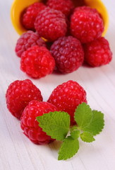 Fresh raspberries and lemon balm on white wooden table, healthy food