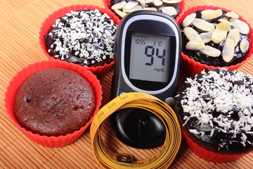 Glucometer, muffins in red cups and tape measure