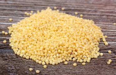 Heap of millet groats on wooden background