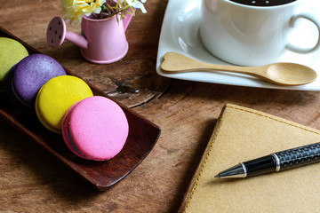 Obraz na płótnie Canvas Colorful macaroons and a cup of coffee with notebook