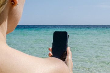 Girl on holyday on the beach with her smartphon connecting with friend
