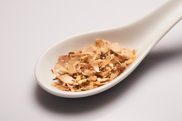 Heap of dry medical herbal tea in white ceramic spoon