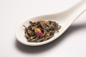 Dry green tea leaves with rose bud in spoon