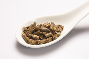 Dry green medical herbal tea in white ceramic spoon