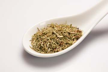 Heap of dry medical herbal tea in white ceramic spoon