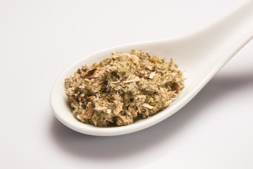 Heap of dry medical herbal tea in white ceramic spoon