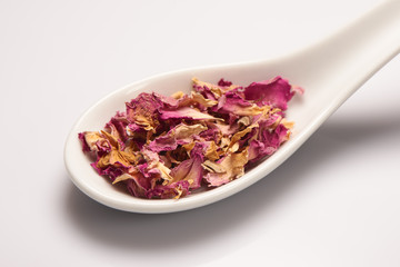 Heap of dry rose leaves in white ceramic spoon