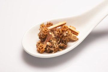 Heap of dry medical herbal tea in white ceramic spoon