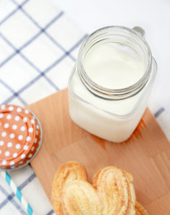 jug of milk on wooden plate with biscuit