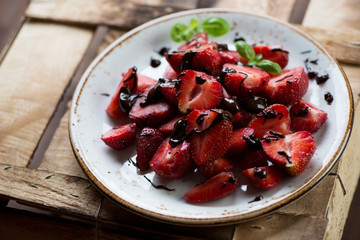 Glass plate with sliced strawberries poured with chocolate
