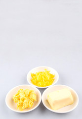 A block of butter, margarine and ghee in white bowls 