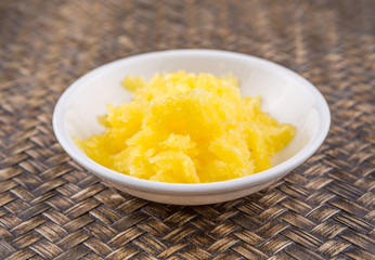 A bowl of Indian ghee in white bowl over wicker background