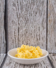 A bowl of margarine in white bowl over wooden background