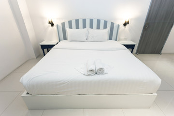 White bed with white cement wall and yellow light on top