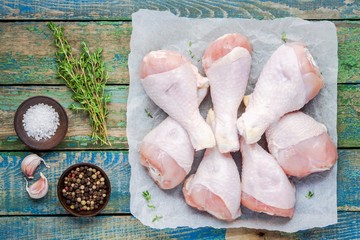 raw organic chicken legs on paper with thyme, salt and pepper