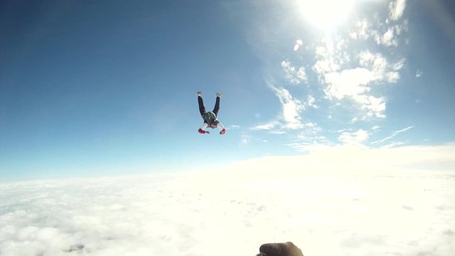 Skydiver through a wonderful blue sky with clouds.