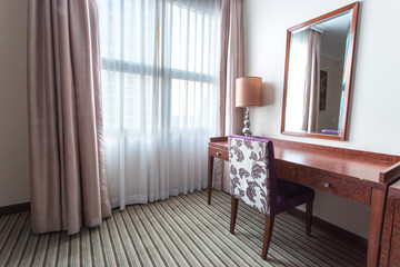 Light shines through white curtains in room with chair and table