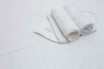 Close up of nice white towels on white bed sheet