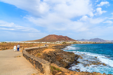 Tourists walking on coastal promenade along ocean in Playa Blanca, Lanzarote, Canary Islands, Spain