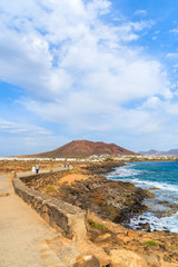 Fototapeta na wymiar Tourists walking on coastal promenade along ocean in Playa Blanca, Lanzarote, Canary Islands, Spain