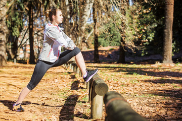 Young fit girl stretching out on bench before exercising in