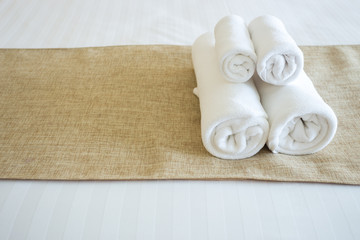 Close up of nice towels on white bed sheet with yellow ribbon