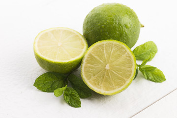Green limes with mint and water drops on white background
