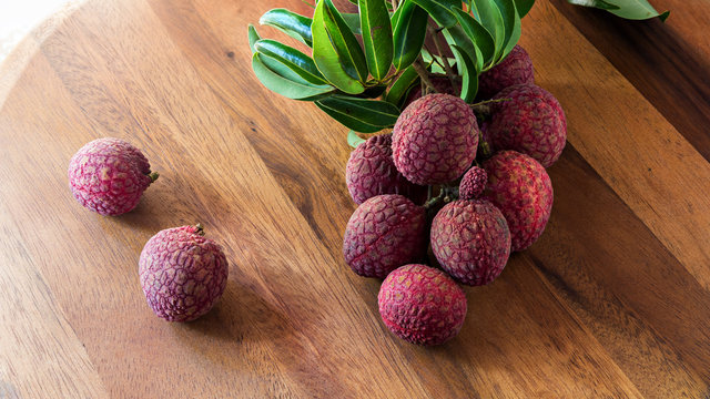 Lychees with leaves on a wooden board, still life