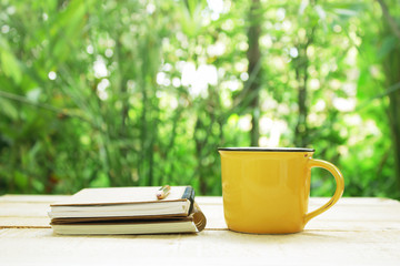Notebook  and coffee in yellow cup on wooden table