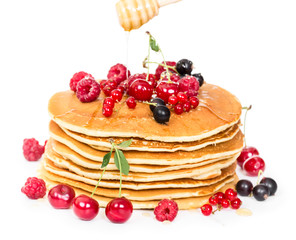 Stack of pancakes with berries and honey