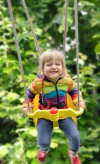 Cute little girl swings. Outdoors scenery.