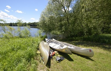 Canoes parked and ready at the waters edge on a sunny summer afternoon