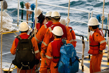 Rig workers using a swing rope prior of being transported to nearby rigs by boat - obrazy, fototapety, plakaty