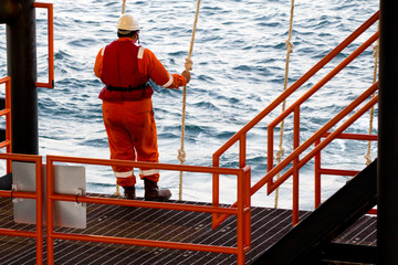 A rig worker holding a swing rope while waiting for a vessel in order to be transported to a nearby...