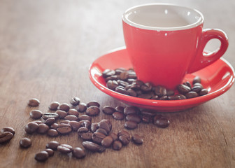 Red coffee cup with coffee beans on wooden table