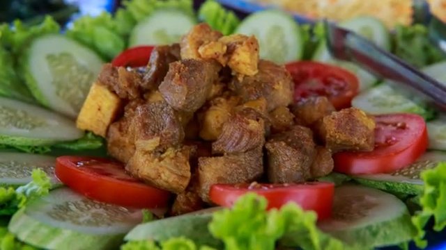 dish with fried meat salad leaves tomatoes and cucumbers	