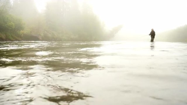 Man Fly-Fishing in a River Enveloped by Fog