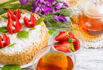 Celebratory cake with strawberries flowers, tea and irises