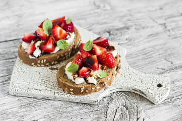 sandwich with strawberries, soft cheese and balsamic vinegar on a light wooden background