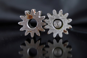 gears working together / Steel cogs of oil pump. Elements with rust, black background, reflection in background