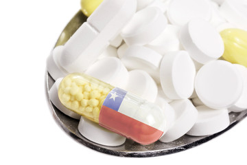 Spoon full of pills and a capsule with the flagdesign of Chile.(