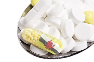 Spoon full of pills and a capsule with the flagdesign of Brunei.