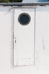 Old white wooden door on the ship with a circular window