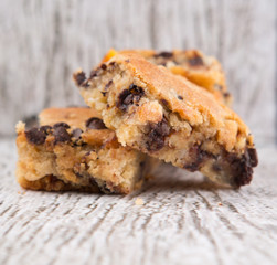 Sweet brownie dessert bar with chocolate chips over wooden background