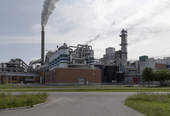 A factory with some and some grass and a road in the foreground