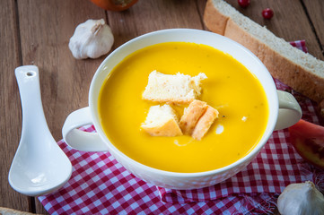 Pumpkin soup with croutons in white bowl