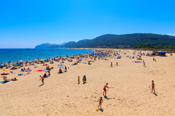 Beach of the Cantabrian coast with tourists with sunbeds and umbrellas on the hot summer day