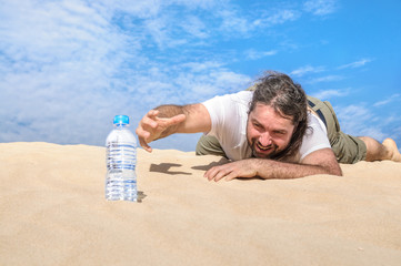 Thirsty man in the desert reaches for a bottle of water - obrazy, fototapety, plakaty