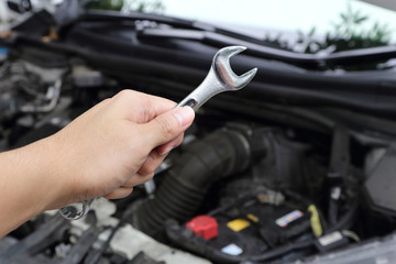 hand with wrench on car engine