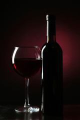 Red wine glass with bottle on black background